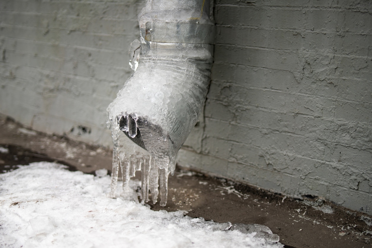A frozen downspout pipe outside of a Michigan home during winter. Learn how to prevent frozen pipes and protect your home!